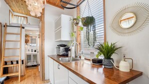 A modern kitchen with wooden countertops, a built-in oven, and hanging plants. - HGTV Featured Tiny Home w Hot Tub Near East 6th St (Austin)