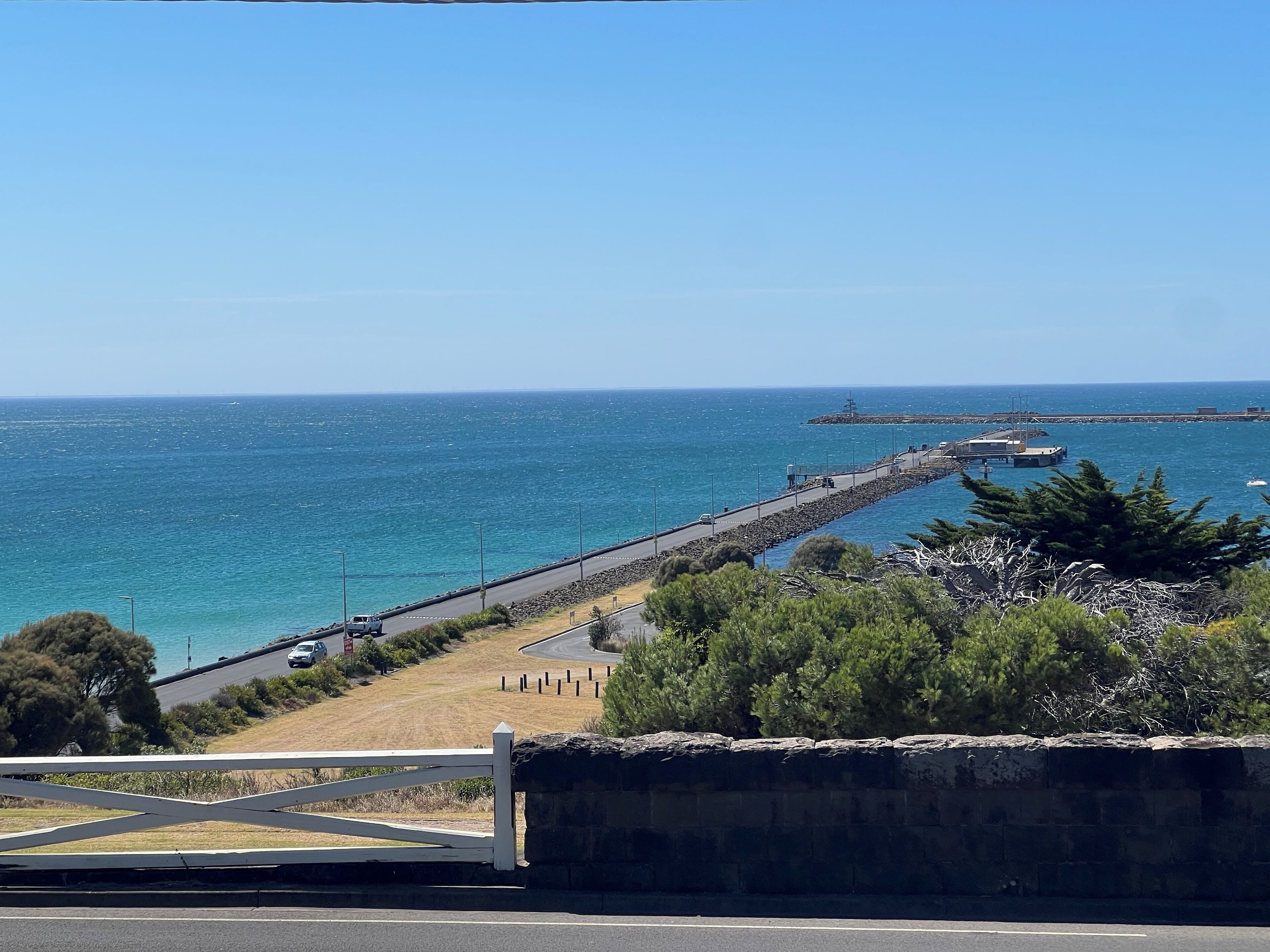 A coastal road with a stone wall and a view of the sea.