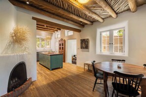 Una cocina amplia con vigas de madera, chimenea y comedor con mesa redonda y sillas.