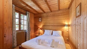 Un dormitorio con paneles de madera, una cama, dos lámparas de noche y un ventanal con cortinas.