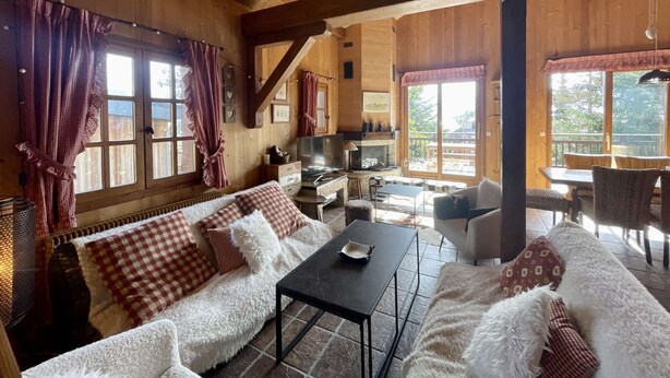 Un interior acogedor de cabaña de troncos con un sofá, una mesa de comedor y una chimenea.