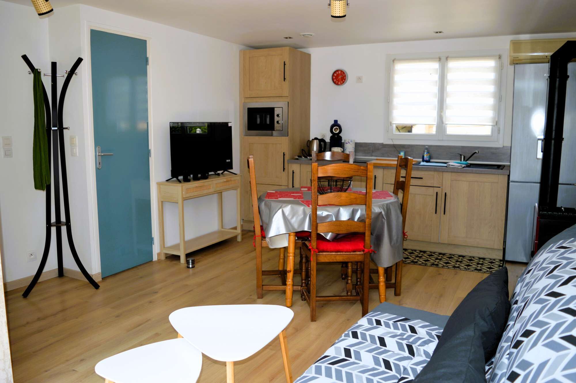 A compact living space with a dining area, kitchenette, and a sofa.