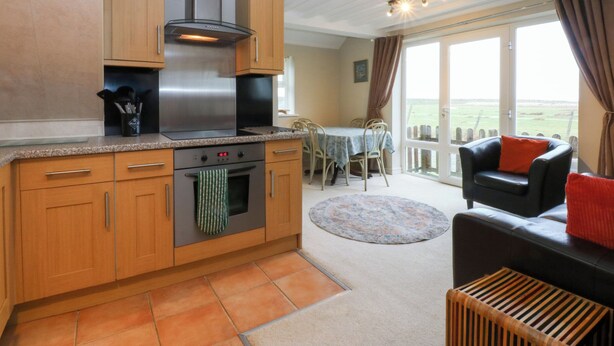 A kitchen with wooden cabinets, a stainless steel range hood, and a dining area with a table and chairs.
