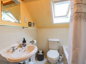 Een badkamer met een wastafel, toilet en raam.