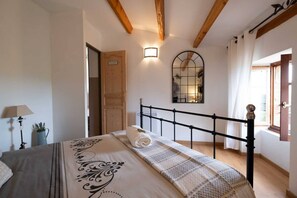 A bedroom with a bed, a nightstand, a lamp, a potted plant, and a wooden door. - L'Écrin du Puech - Pool & SPA - Gym room (Teillet)