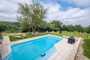 A rectangular swimming pool with a tiled deck, surrounded by lounge chairs and a small table. - L'Écrin du Puech - Pool & SPA - Gym room (Teillet)