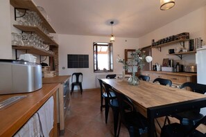 A modern kitchen with wooden shelves, a dining table, and chairs.