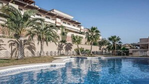 A swimming pool with palm trees and a building in the background.