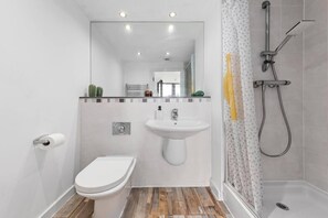 A small bathroom with a toilet, sink, and shower.