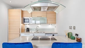 Una cucina moderna con isola centrale, elettrodomestici in acciaio inossidabile e sedie blu.