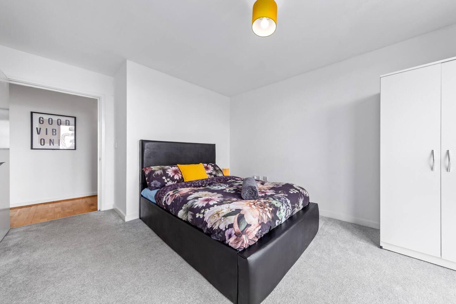 Un dormitorio con cama, armario y un cartel enmarcado en la pared.