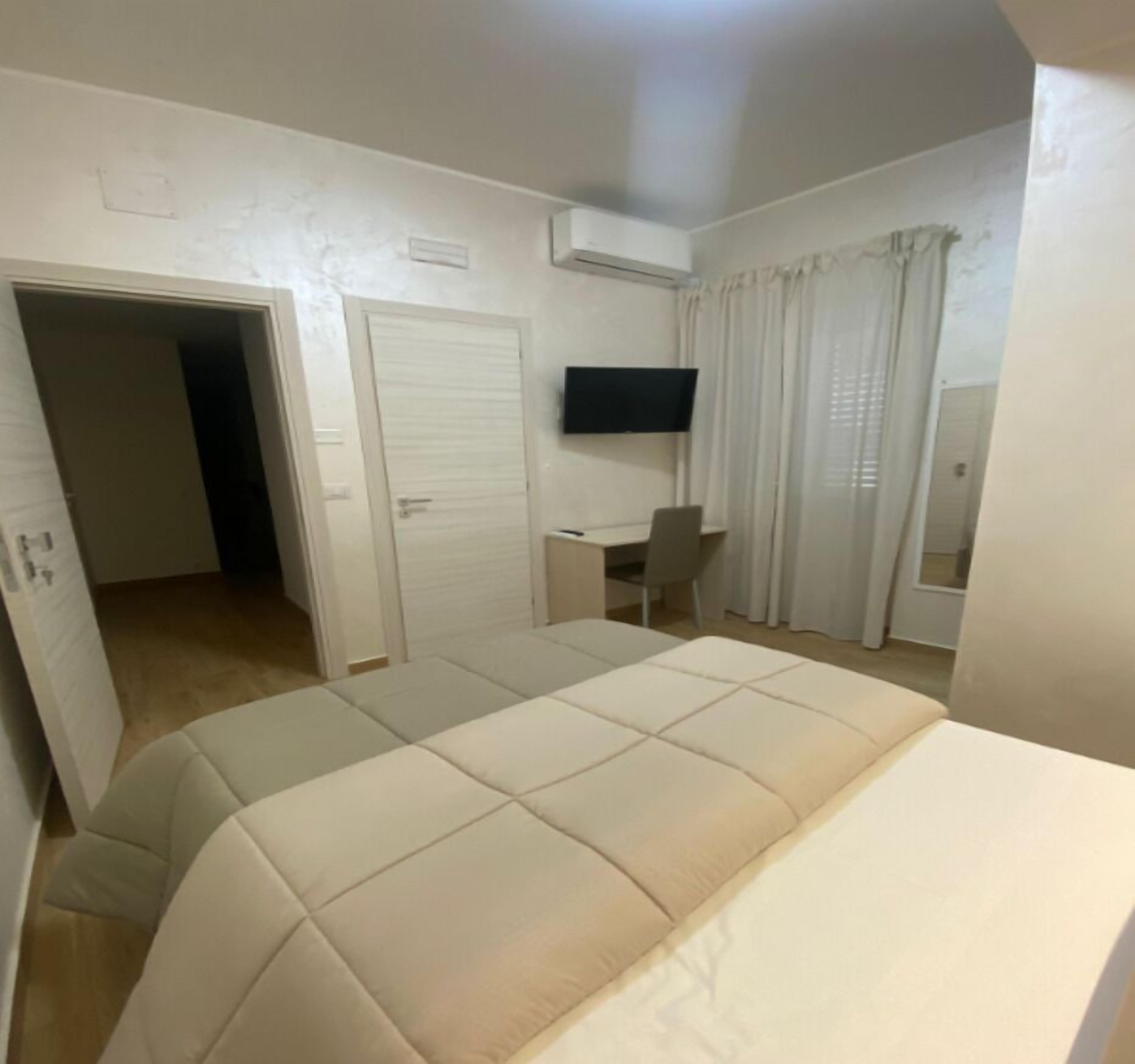 Une chambre à coucher comprenant un lit, un bureau, une chaise, une télévision et une armoire.