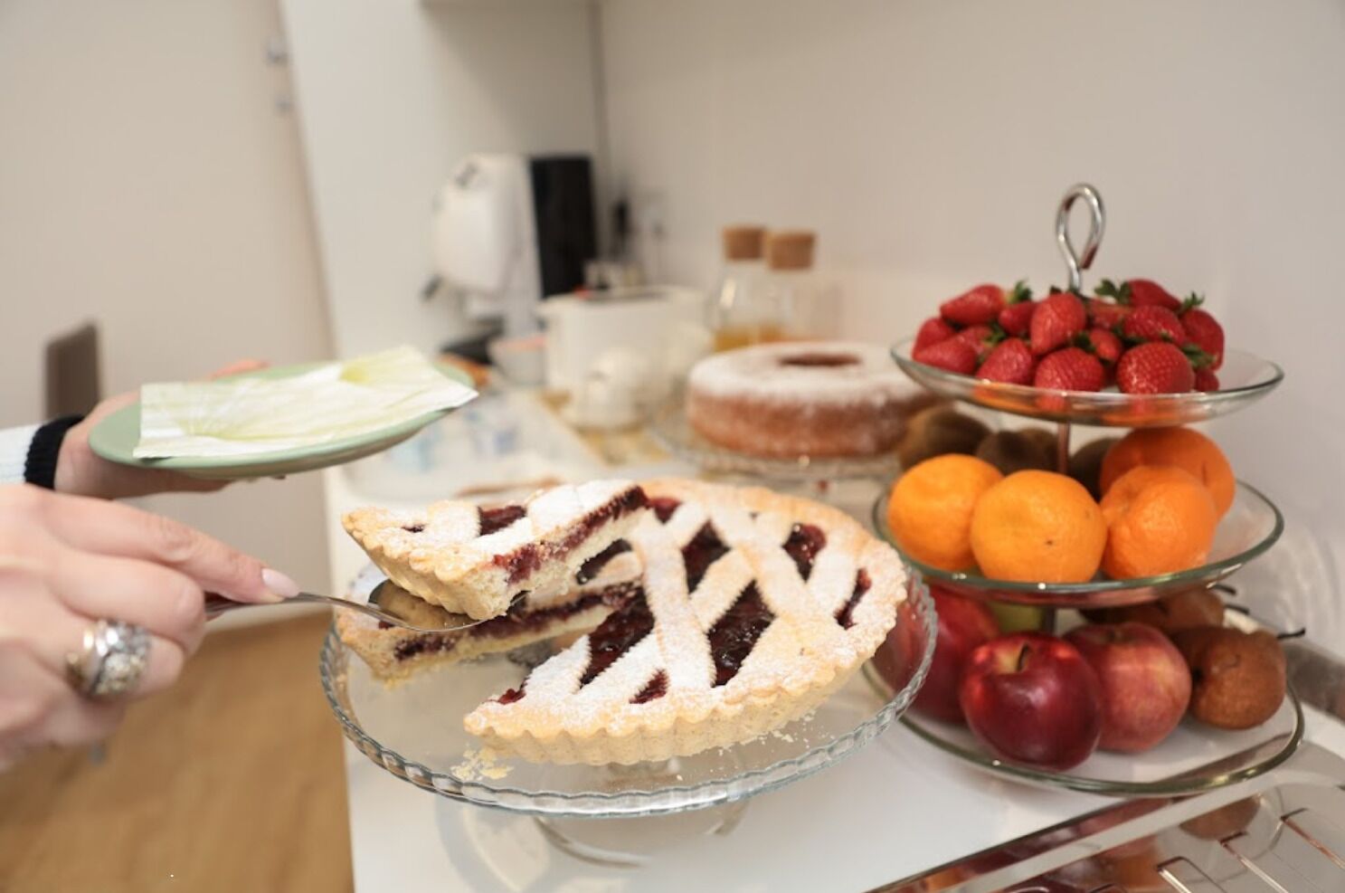 Ein Desserttisch mit Kuchenstück, Erdbeeren, Orangen und Äpfeln.