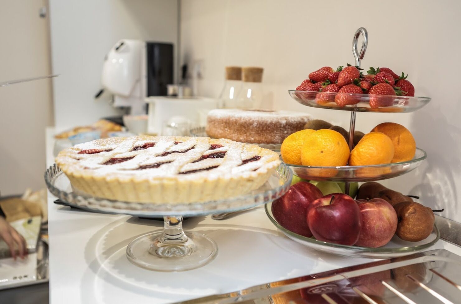 A buffet table with a variety of desserts including a pie, a fruit tray with strawberries and oranges, and a plate of apples.
