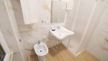 Ein Badezimmer mit Marmorwand, Waschbecken, Bidet und Spiegel.