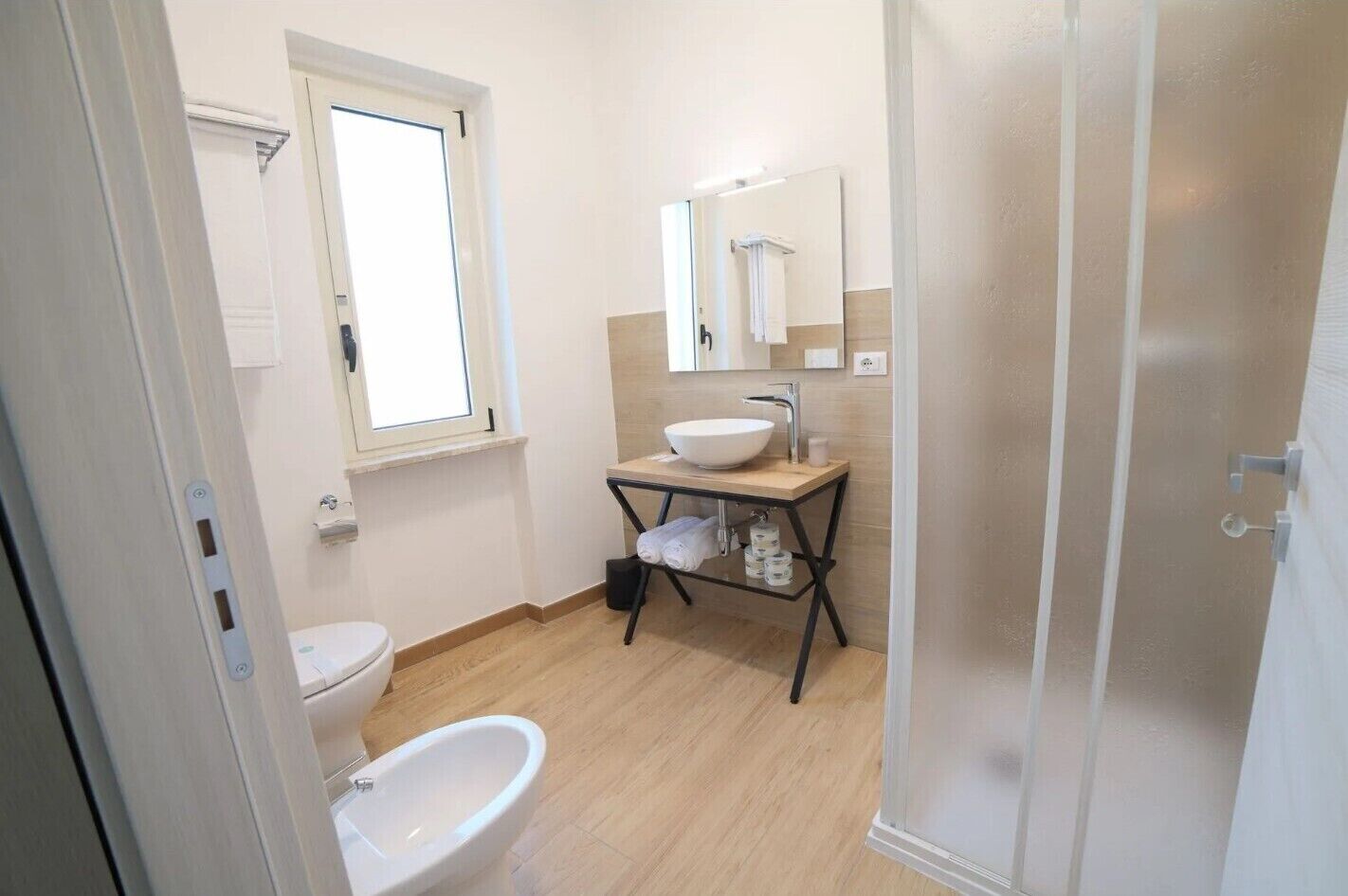 A bathroom with a toilet, bidet, sink, and mirror.