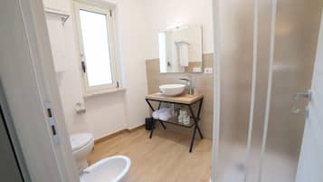 A bathroom with a toilet, bidet, sink, and mirror.