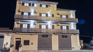 A multi-story building with balconies, large garage doors, and multiple air conditioning units.