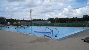 Una piscina con trampolín y un pequeño puente.