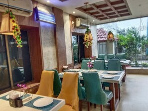 A restaurant with indoor dining area, multiple tables, chairs, and hanging lights. - Royal Sea View (Kanthi)