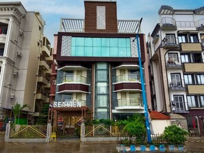A multi-story hotel with a central atrium, balconies, and a visible entrance. - Royal Sea View (Kanthi)