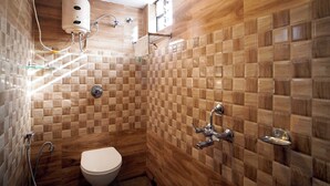 A bathroom with a wooden checkered tile wall, a white toilet, and a shower area with a glass-enclosed shower. - Royal Sea View (Kanthi)