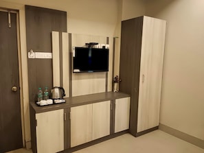 A kitchenette with a flat-screen TV, a coffee maker, and a small countertop. - Royal Sea View (Kanthi)