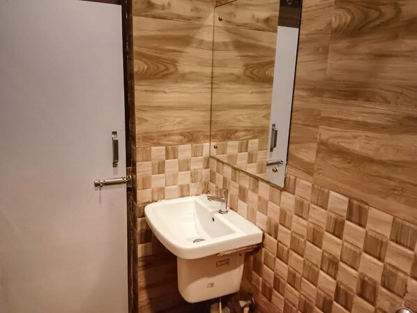 A bathroom with a white sink, a mirror above it, and a wooden wall. - Royal Sea View (Kanthi)
