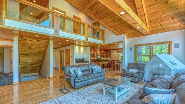 A spacious loft-style living area with a high ceiling, wooden beams, and a large sofa set. - Luxe Cabin at Bretton Woods (Carroll)