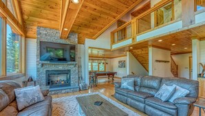 A spacious living room with a stone fireplace, leather sofas, and a wooden ceiling. - Luxe Cabin at Bretton Woods (Carroll)