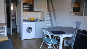 A compact kitchen with a washing machine, microwave, and a small dining area with a table and chairs.