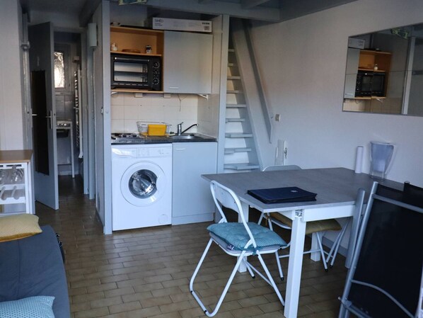 A compact kitchen with a washing machine, microwave, and a small dining area with a table and chairs.