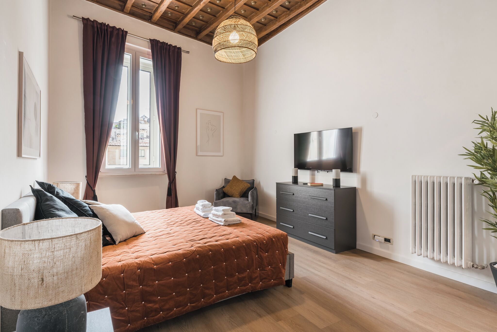 A bedroom with a bed, a dresser, a TV, and a radiator.