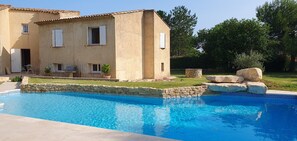Une maison avec une piscine, des murs en pierre et un espace patio.