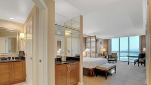 A hotel room with a large bed, a desk, a chair, a small table, a bench, a large mirror, and a view of the outside. - MGM Signature-Mountain View  Deluxe Spa 24th floor (Las Vegas)