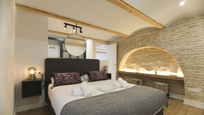 Quarto com uma cama grande, teto de madeira, paredes de pedra e uma pequena janela.