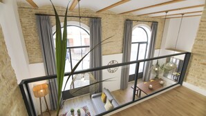Um amplo loft com paredes de tijolos aparentes, grandes janelas, teto de madeira e design de interiores moderno.