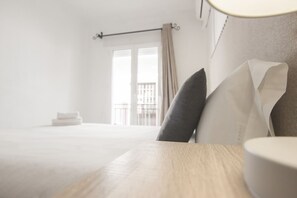 A hotel room with a bed, a bedside table, and a view of a balcony. - RentalSevilla Sleeping in the Jewish quarter of Seville (Sevilla)