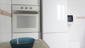 Une cuisine avec un four blanc, un four à micro-ondes et un saladier bleu posé sur le plan de travail.