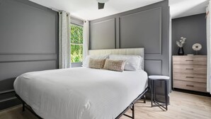 A bedroom with a large bed, a ceiling fan, a dresser, and a window with curtains. - Beautiful Penthouse Condo Just Steps to King (Charleston)