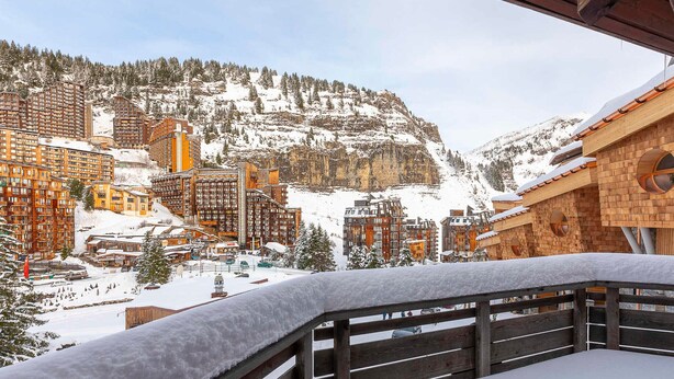 Une ville de montagne enneigée, avec des bâtiments modernes et une structure en bois dotée de fenêtres rondes.