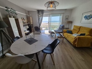 Ein modernes Wohnzimmer mit Essbereich, einer Couch und einem Balkon mit Blick.