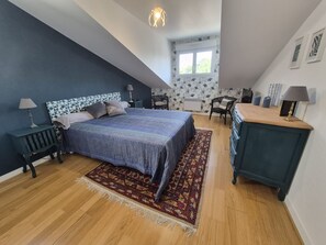 Une chambre à coucher avec un lit, un bureau, une chaise, une commode et une fenêtre.