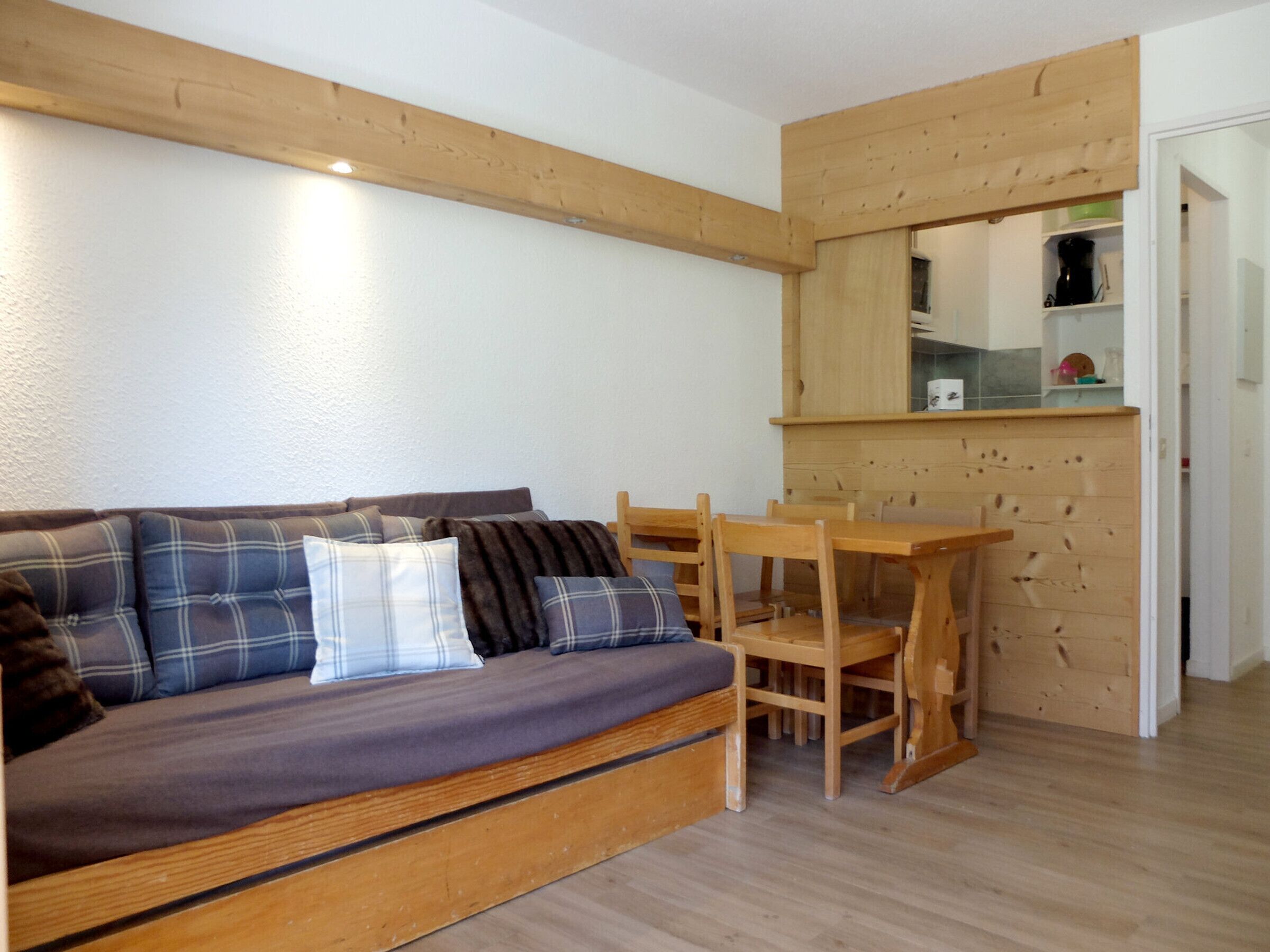 A cozy living area with a sofa, wooden chairs, and a small wooden table.
