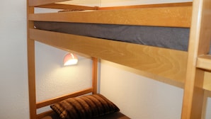 Un letto a castello con struttura in legno, un materasso grigio e un cuscino marrone.