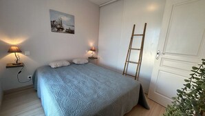 Un dormitorio con cama, lámparas de noche, un cuadro, una escalera y una puerta.