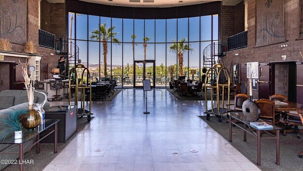 A spacious lobby with a large glass wall offering a view of palm trees and mountains. - Best location in Lake Havasu! Walk to London Bridge!  Heated Pool & Golf. (Lake Havasu City)