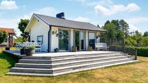 Ett modernt hus med en inglasad veranda, stora fönster och ett trädäck.