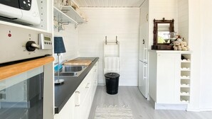 Ett modernt kök med vita skåp, en svart bänkskiva och en diskho i rostfritt stål.
