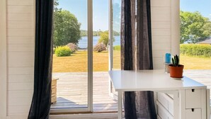 Ett rum med en stor skjutdörr i glas som leder ut till en terrass, ett vitt skrivbord och en krukväxt.